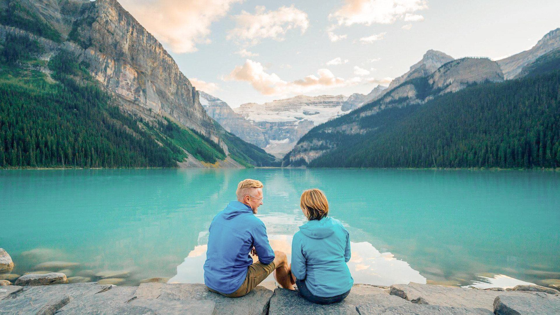Couple sitting at Lake Louise looking toward Victoria Glacier