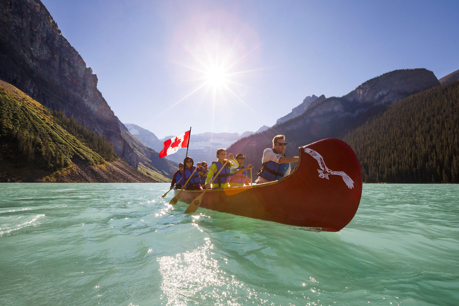 Group canoeing on Lake Louise with Canadian flag