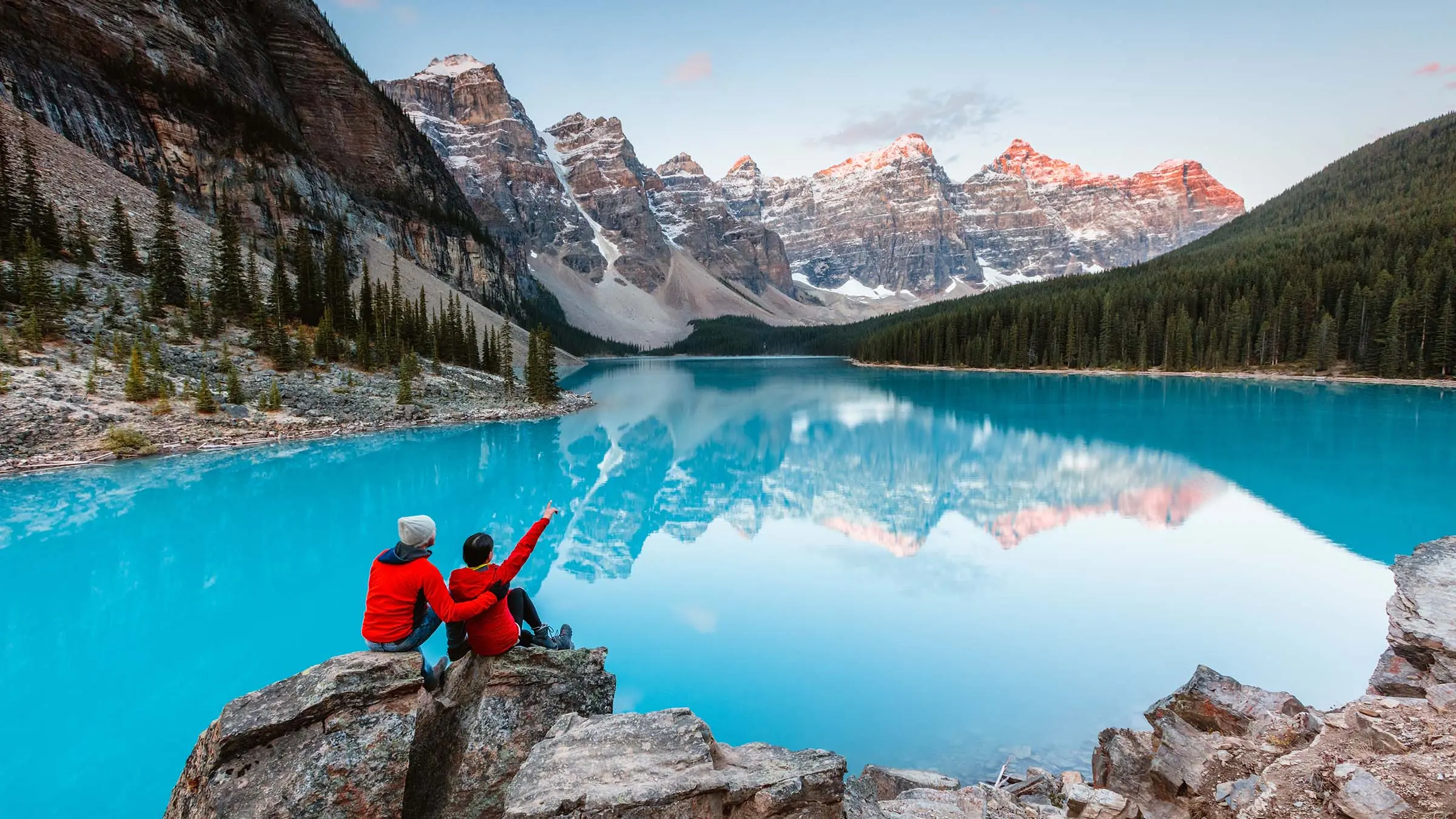 Two guests sitting on rocks overlooking Moraine Lake and the Valley of the Ten Peaks