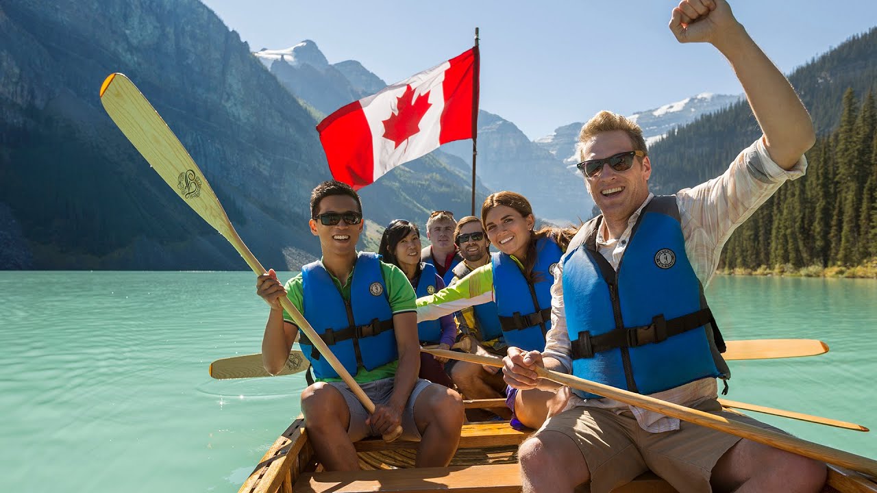 Guests paddling a voyageur canoe on a mountain lake